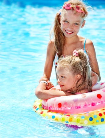 Children sitting on inflatable ring in swimming pool.の写真素材