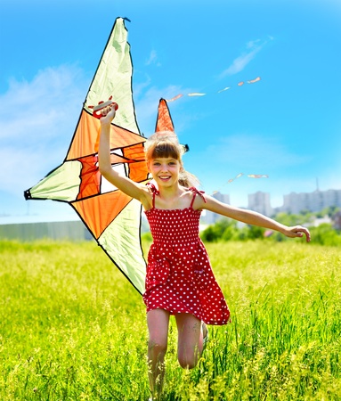 Child flying kite outdoor. little girl running across  green grass.の写真素材