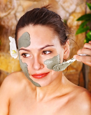 Beautiful girl having clay body mask apply by beautician.の写真素材