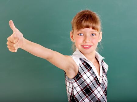 Happy schoolchild in classroom near blackboard.の写真素材