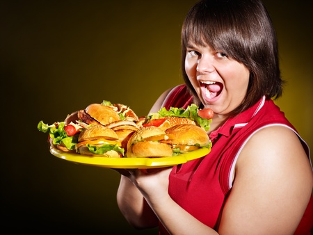 Overweight woman holding hamburger.の写真素材