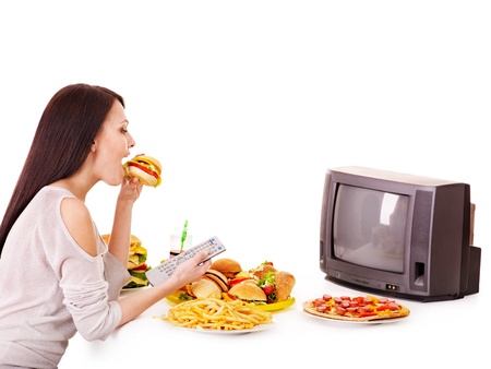Woman eating fast food and watching TV. Isolated.の写真素材