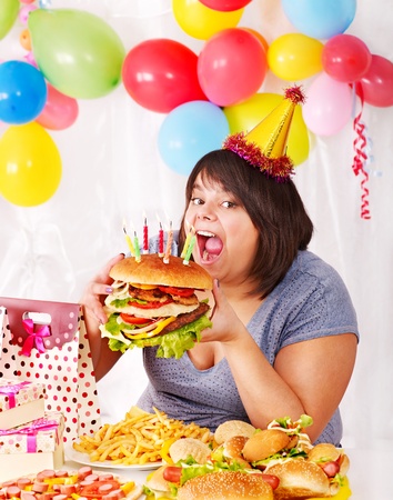 Woman eating hamburger at birthday. Isolated.の写真素材