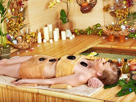 Woman getting stone therapy massage in bamboo spa.の写真素材