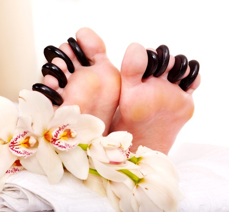 Woman receiving hot stone massage on feet. Isolated.の写真素材