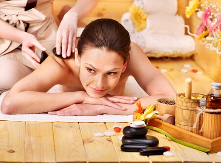 Woman getting stone therapy massage in wooden spa.の写真素材