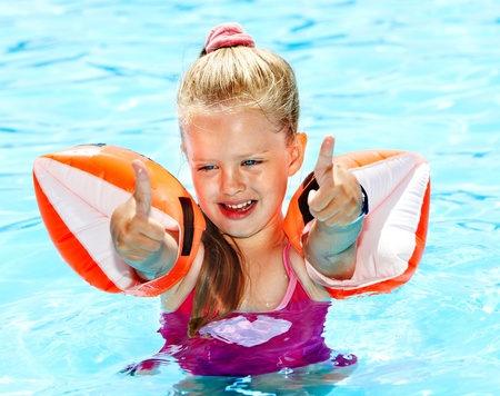 Child with armbands playing in swimming pool. Summer outdoor.の写真素材