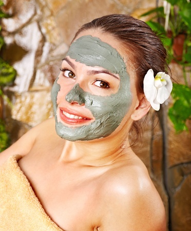 Beautiful woman having clay facial mask apply by beautician.の写真素材