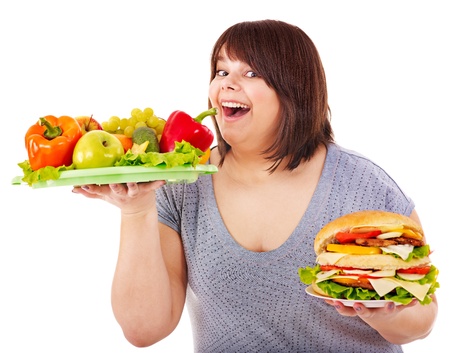 Woman choosing between fruit and hamburger. Isolated.の写真素材