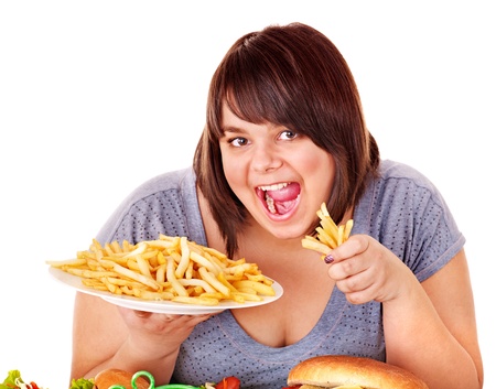 Overweight woman eating French fries. Isolated.の写真素材