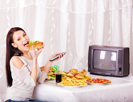 Woman eating fast food and watching TV. Isolated.の写真素材