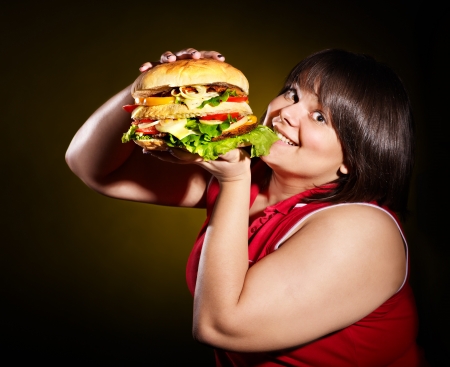 Overweight woman eating hamburger.の写真素材
