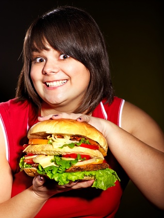 Overweight woman holding big hamburger.の写真素材