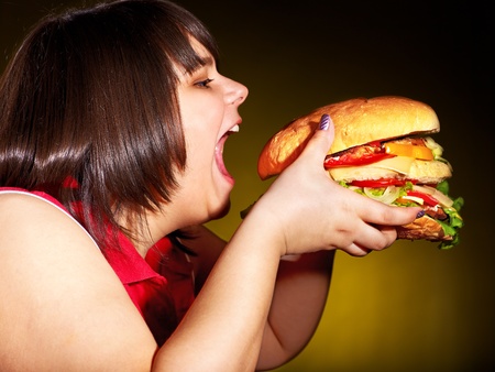 Overweight hungry woman eating hamburger.の写真素材