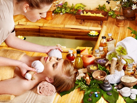 Young woman getting facial herbal massage ball.の写真素材