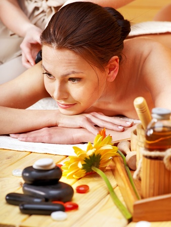 Woman getting stone therapy massage in wooden spa.の写真素材