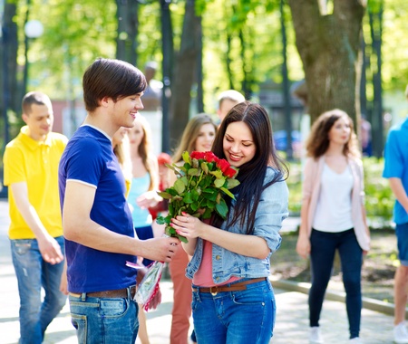 Couple of teenager on date outdoor. Group of people in background.の写真素材