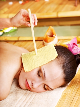 Woman getting massage with ear candle in bamboo spa.の写真素材
