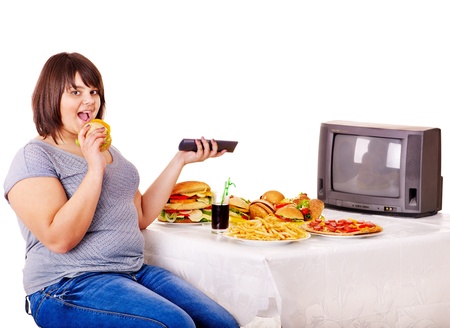 Overweight woman eating fast food and watching TV. Isolated.の写真素材