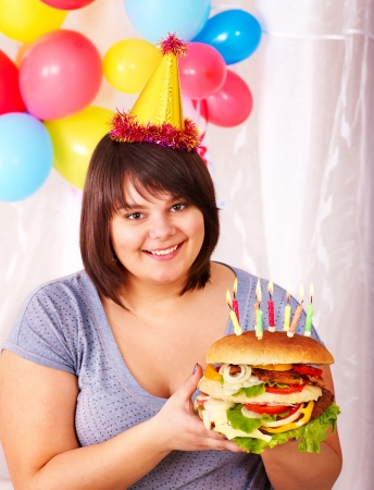 Overweight woman eating hamburger at birthday. Isolated.の写真素材
