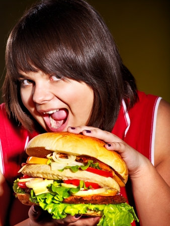 Overweight woman eating hamburger.の写真素材