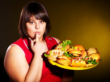 Overweight woman eating hamburger.の写真素材