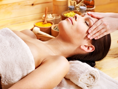 Woman getting facial  massage in wooden spa.の写真素材
