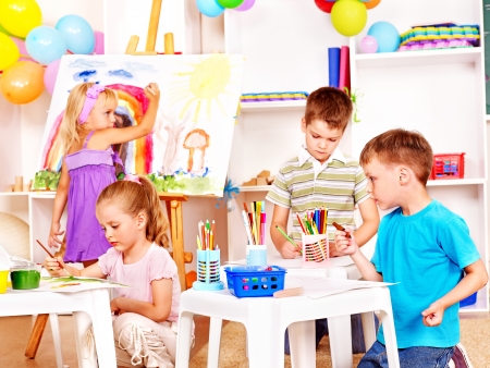 Group child painting at easel in school.の写真素材