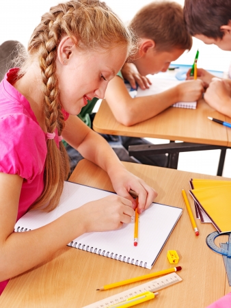 Group of school child sitting on desk in classroom.の写真素材