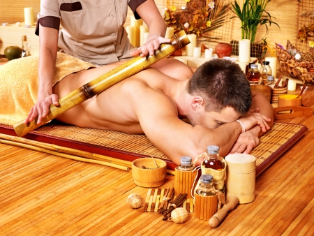 Man getting bamboo massage. Female therapist.の写真素材