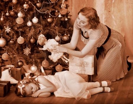 Child with mother receiving near Christmas tree. Black and white retro.の写真素材