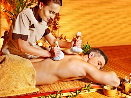 Man getting herbal ball massage treatments  in spa.の写真素材