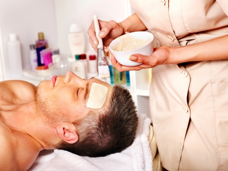 Man with clay facial mask in beauty spa.の写真素材