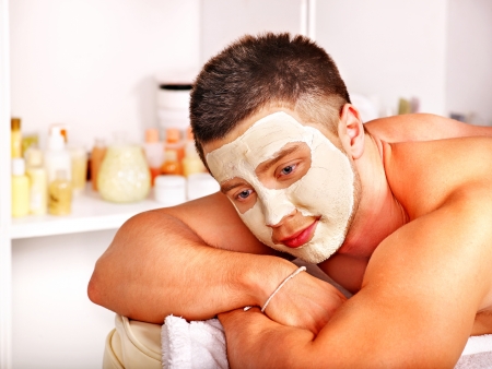 Man with clay facial mask in beauty spa.の写真素材