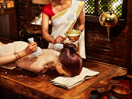 Woman having ayurvedic massage with pouch of rice.の写真素材