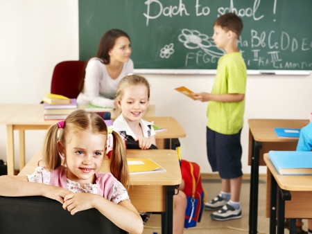 Children with teacher in classroom near blackboard .の写真素材
