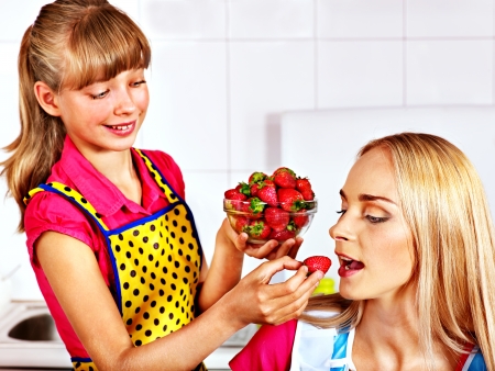 Happy child feed mother  at kitchen.の写真素材