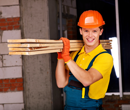 Happy man in builder uniform carry boards indoor.の写真素材