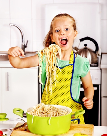 Children  eating spaghetti at kitchen.の写真素材