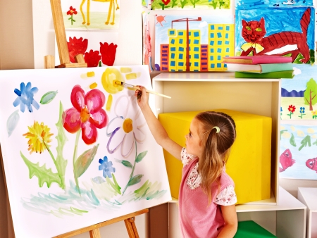 Child painting at easel in art class の写真素材