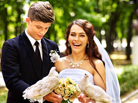 Bride and groom holding dove in park outdoor.の写真素材