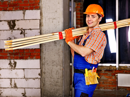 Happy man in builder uniform carry boards indoor.の写真素材