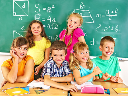 Group of school child sitting on desk in classroom.の写真素材