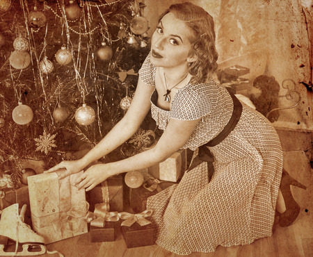 Woman receiving gifts under Christmas tree. Sepia toned.の写真素材