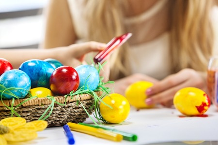 Children paint Easter eggs at home. Focus on eggs. Girl background.の写真素材