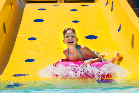 Child on water slide at aquapark. Summer holiday.