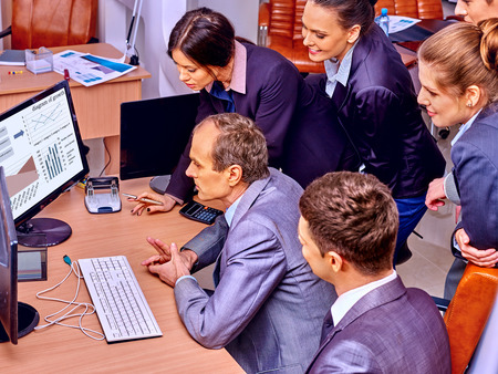 Happy group business people together  in office. Looking at pc.