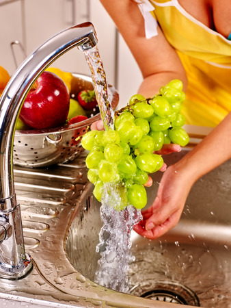 Female hands  washing fruit at kitchen.の写真素材