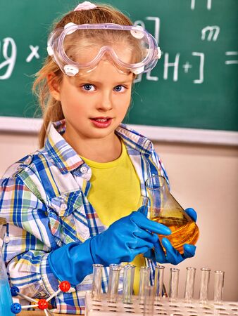 Child in blue rubber glove holding flask in chemistry class.の写真素材