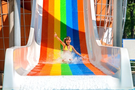 Happy child girl in bikini sliding water park.の写真素材